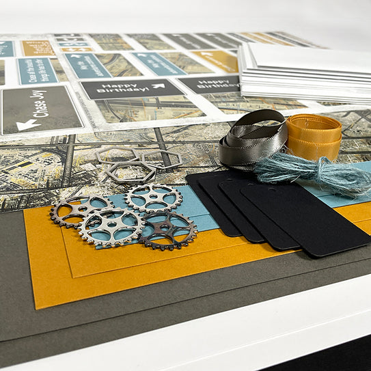 Crafting materials including gears, ribbons, and cardstock on a table.