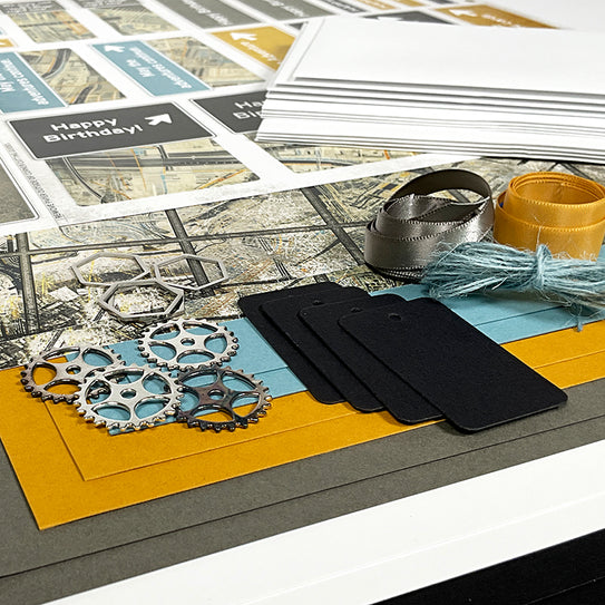 Collection of stationery items including cards, ribbons, and gears on a textured surface.