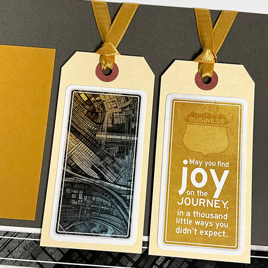Two gold gift tags with ribbons on a textured surface